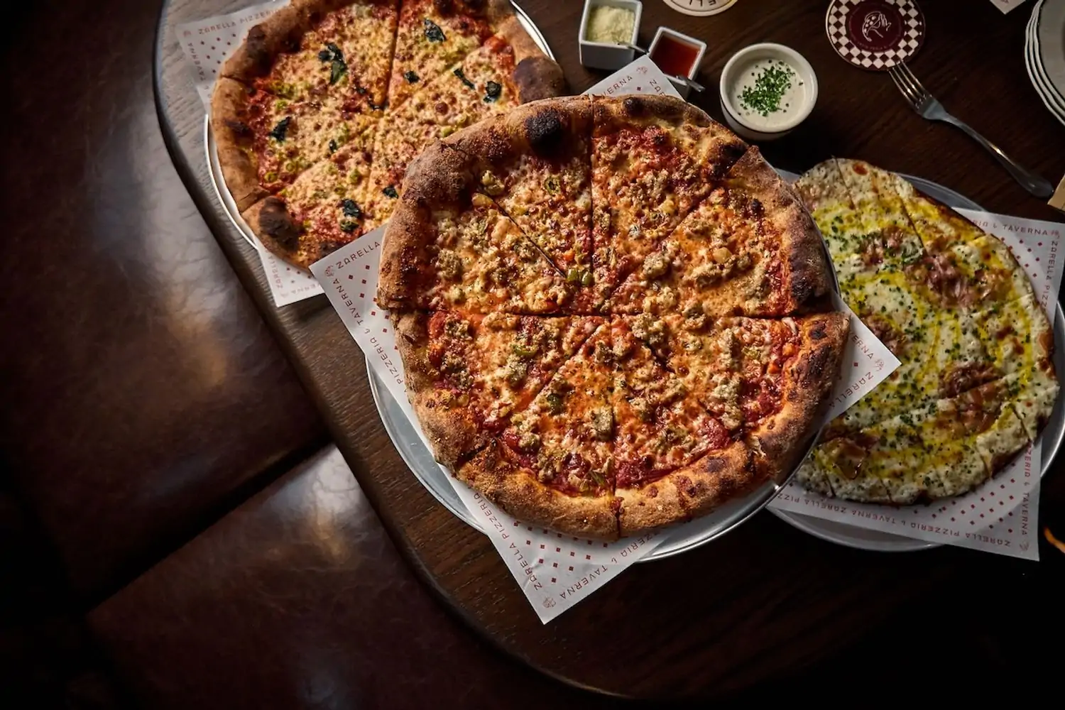 A sausage pizza, a cheese pizza, and a vegetable pizza with sides of sauces like garlic ranch at Zarella Pizzeria & Tavern, one of the Chicago best new restaurants on OpenTable.