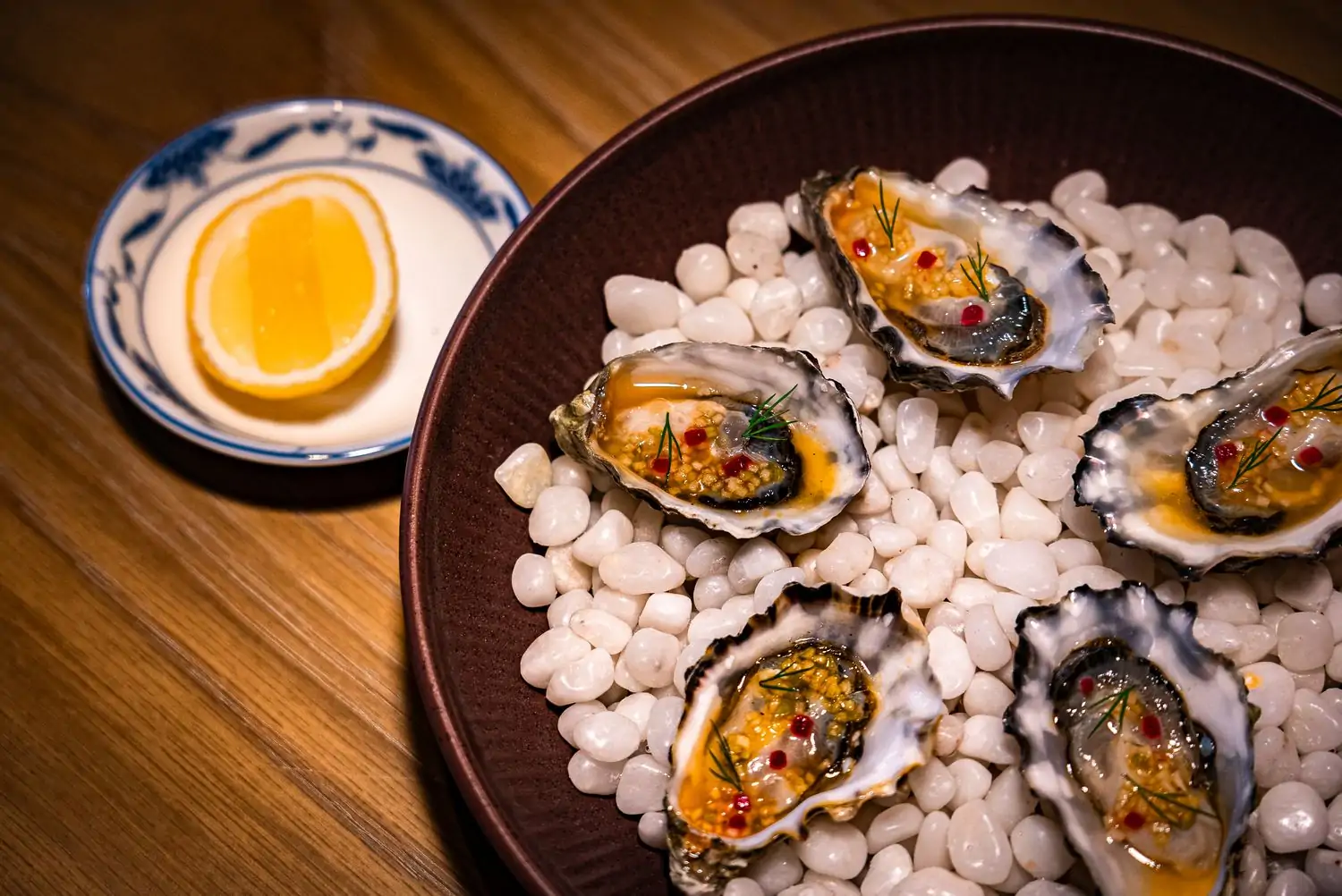 Five oysters with passionfruit-chili essence and shallots and a side of lemon wedge at Eylan, one of the best new restaurants in San Francisco on OpenTable.