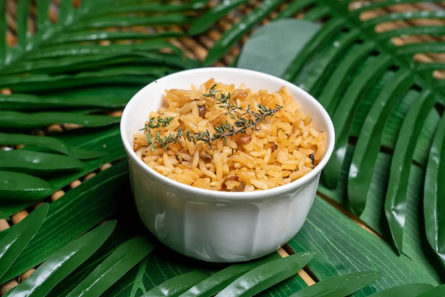 A small dish of white rice set on a backdrop of palm leaves from OpenTable from Trini Vybez, one of the best vegetarian restaurants in DC