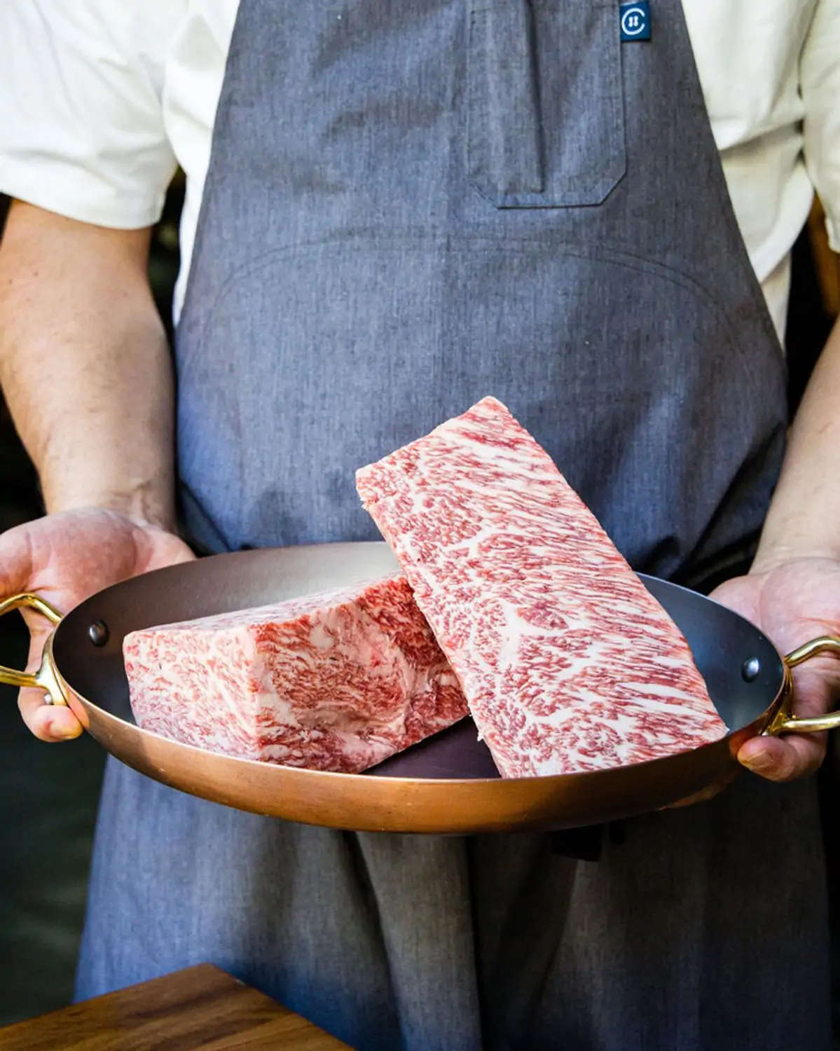 A chef holds a pan with uncooked cuts of grade A5 wagyu at Nike Steakhouse, one of the best steak restaurants in San Francisco, on OpenTable.
