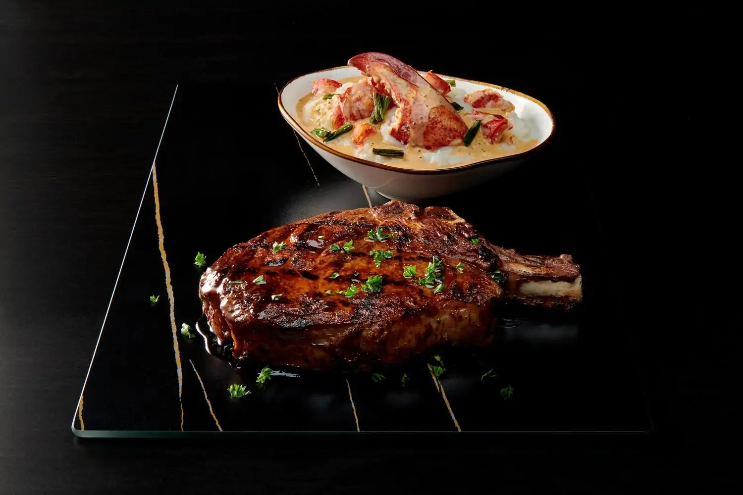 A sizable bone-in ribeye steak next to a bowl of lobster bisque with an exposed claw at Mastro’s Steakhouse in San Francisco on OpenTable.