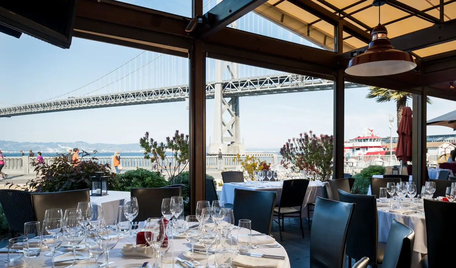 White tablecloths cover circular tables on an outdoor patio with views of the Golden Gate Bridge at EPIC Steak, one of the San Francisco best steakhouse restaurants on OpenTable.
