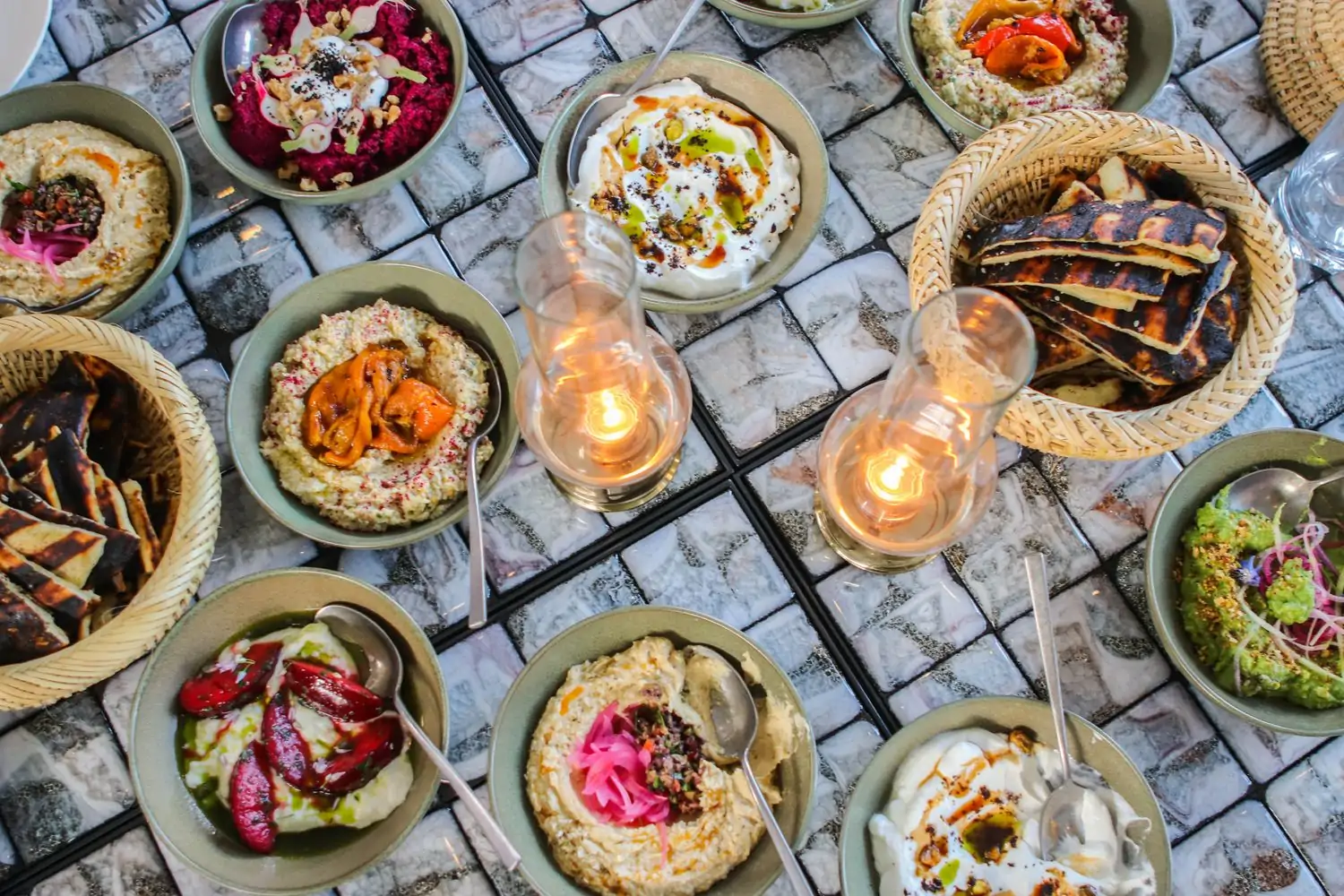 A tabletop filled with small dishes including whipped feta, hummus with roasted peppers, grilled flatbread, cauliflower, and more at Calabra at Santa Monica Proper, one of the best Mediterranean restaurants Los Angeles at OpenTable.