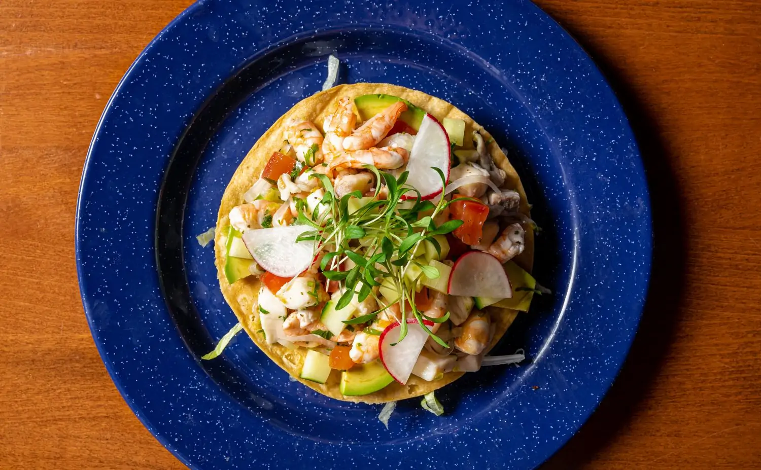 A blue plate holds a Tostada Ceviche Costeño, a taco with fresh Mexican ingredients, at Arnaldo Richards' Picos, one of the best Mexican restaurants in Houston on OpenTable.