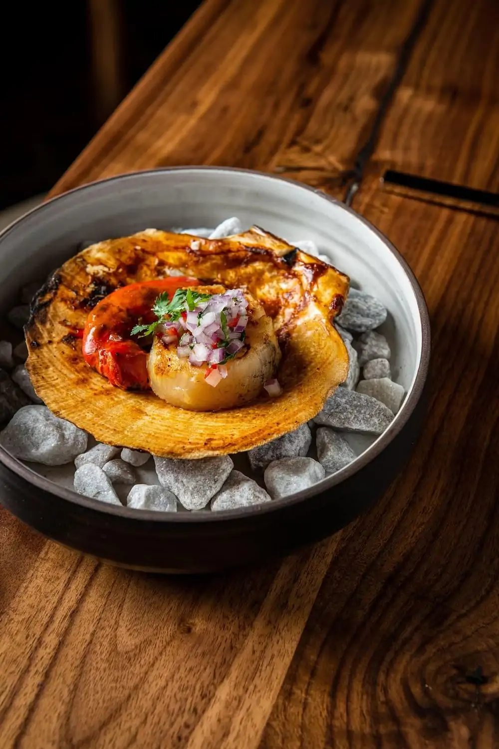 A grilled scallop served with shell on a bed of coals at Causa, a MICHELIN Star restaurant in Washington, DC, on OpenTable.