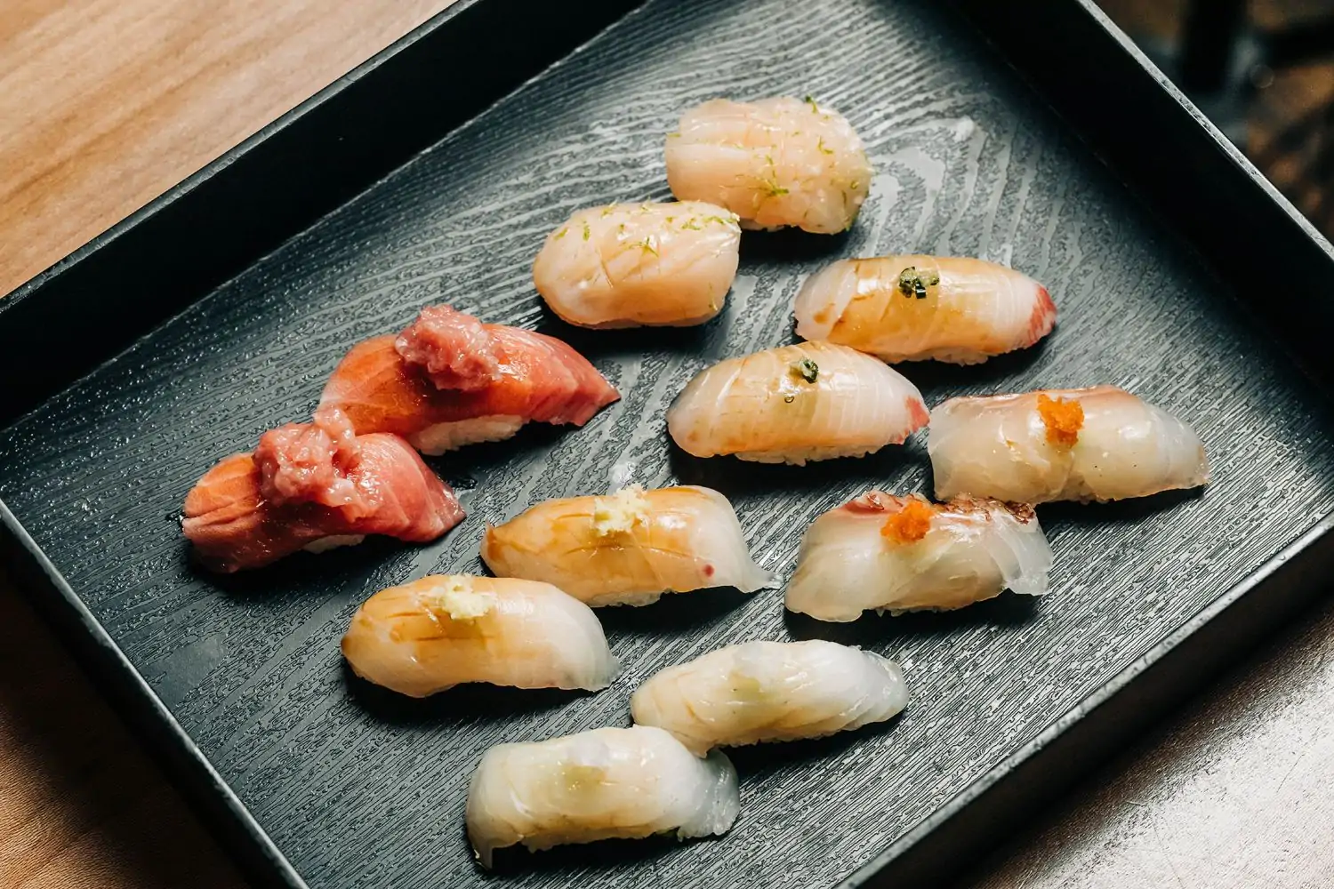 Assorted nigiri sushi with different toppings, including red fish and white fish, arranged on a black textured tray at Sushi San, one of the best sushi restaurants in Chicago, available to book on OpenTable for a private omakase experience.