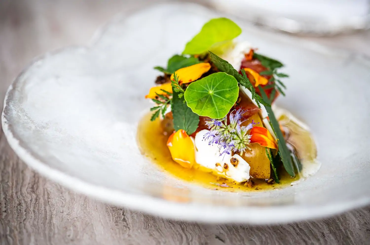 An amuse-bouche decorated with edible flowers and leaves at Bresca, one of the best MICHELIN-starred restaurants in Washington DC, on OpenTable.