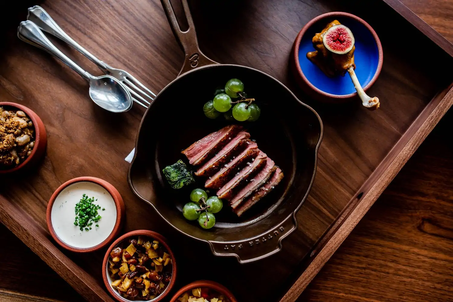 A skillet holds pork, grapes, and sauteed greens at The Dabney, one of the best Michelin-Starred restaurants in Washington, DC.