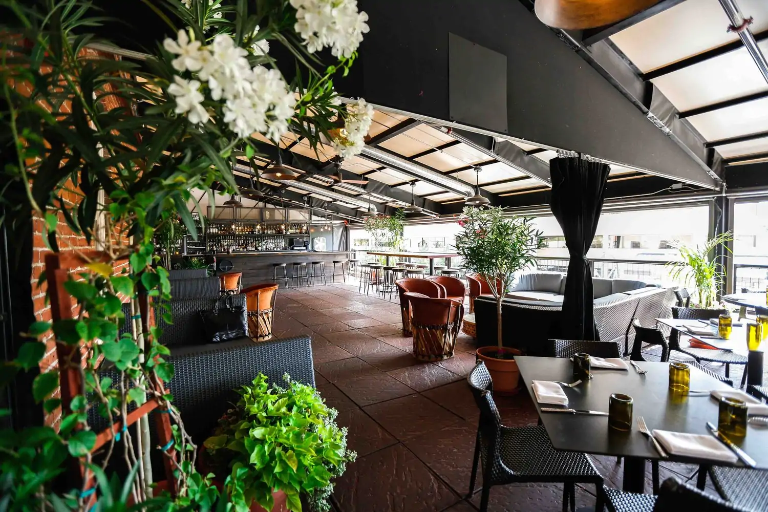 A large covered deck with big tables and high chairs, a bar area, a secluded section with a large couch, and plenty of booths, all for socializing at Tamayo Restaurant (Downtown/LoDo), one of the best Mexican restaurants in Denver. Book on OpenTable.