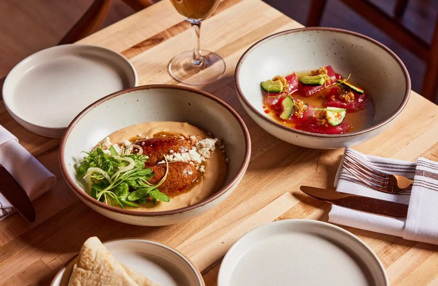 Two ceramic bowls are filled with Mexican dishes on a wooden table with fine silverware and cloth napkins at Alma Fonda Fina (LoHi), Denver. Reserve a table on OpenTable.