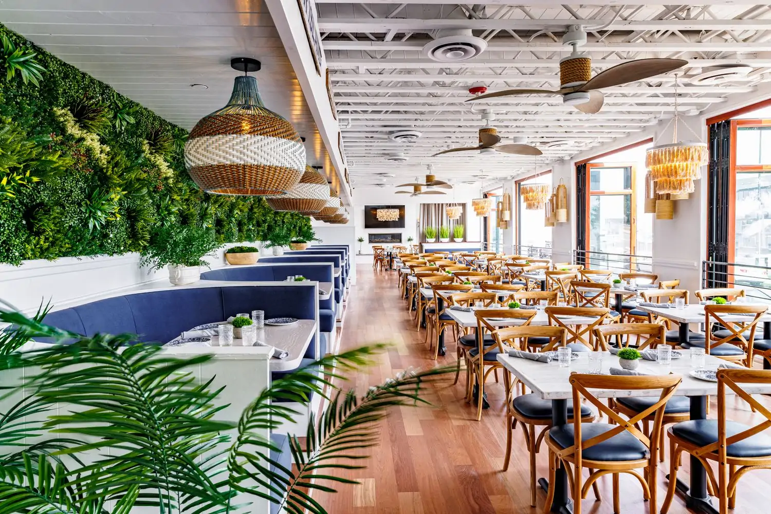 A light-filled dining room with greenery and banquettes at The Hampton Social, one of the best restaurants for kids in Denver. Book on OpenTable.