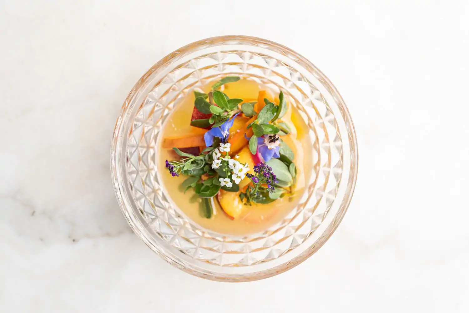 An overhead shot of a dish of fruit accented by flowers at Citrin in Santa Monica. Book on OpenTable.
