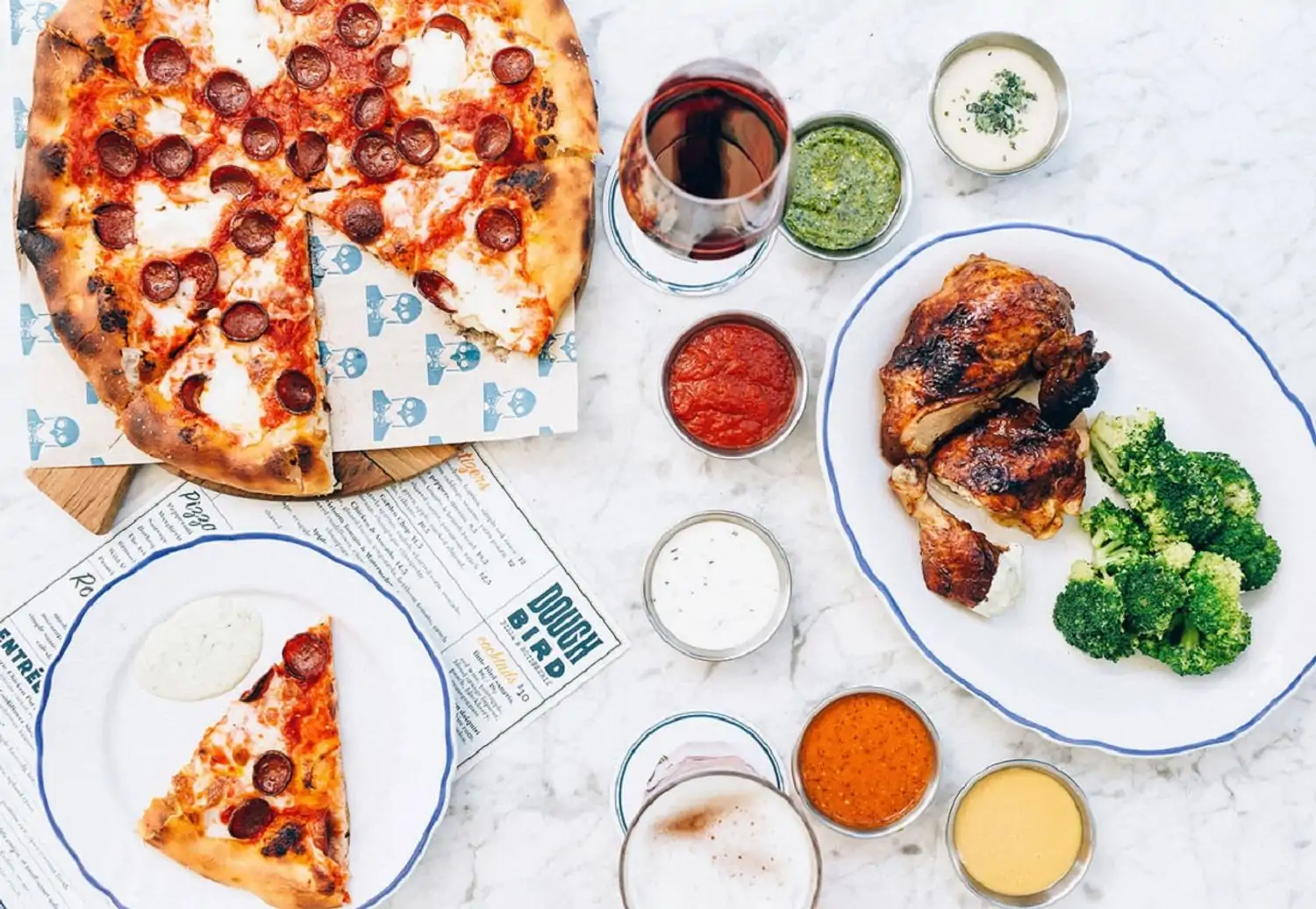 A stylish dining table featuring pizza, chicken wings, and fresh vegetables at Doughbird, one of the Nashville family restaurants on OpenTable.