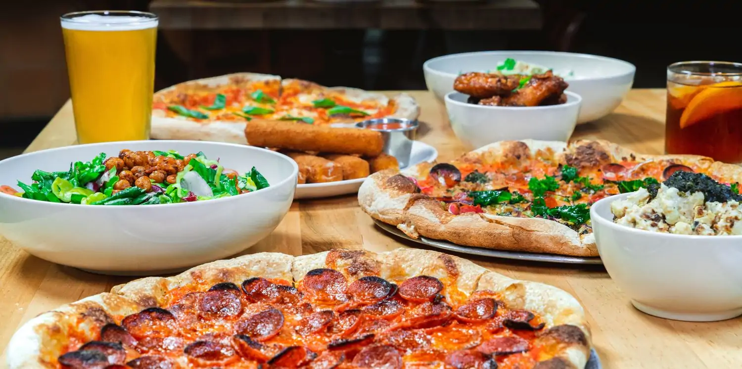 A table with pizzas, and American-Italian sides at Love Supreme Pizza Bar in Austin. Reserve a table on OpenTable.