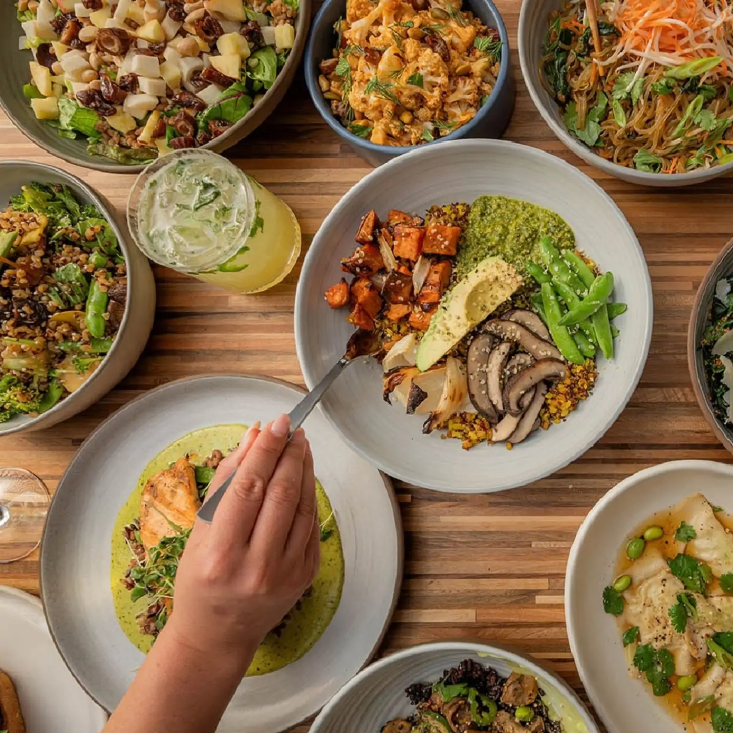 A table setting containing plates of colorful salads, vegetables, and noodles at True Food Kitchen, bookable on OpenTable.
