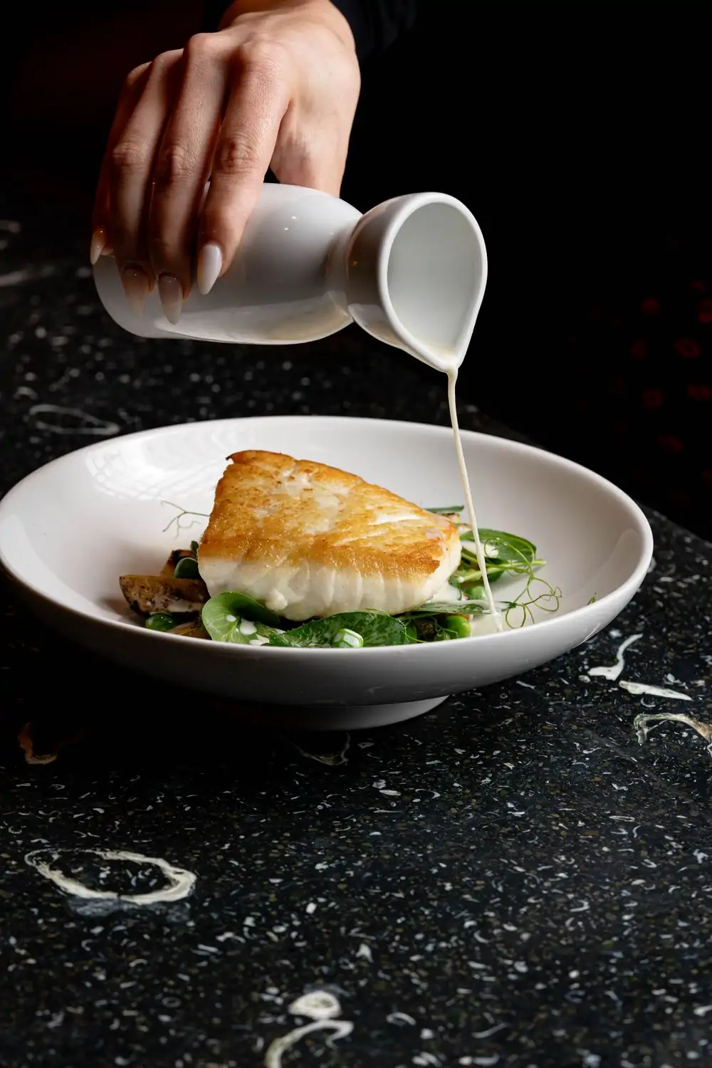 Sauce finishes a dish of seared fish and greens at Water Grill, one of the best restaurants in Santa Monica. Book on OpenTable.