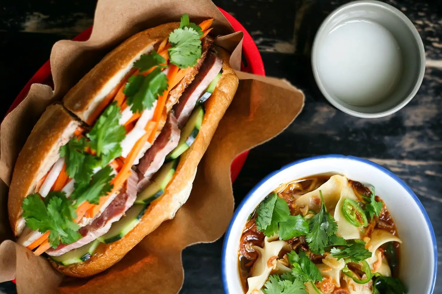 A close-up of a bánh mì sandwich alongside a bowl of noodles at Elizabeth St Cafe, one of the best family restaurants in Austin. Book on OpenTable.