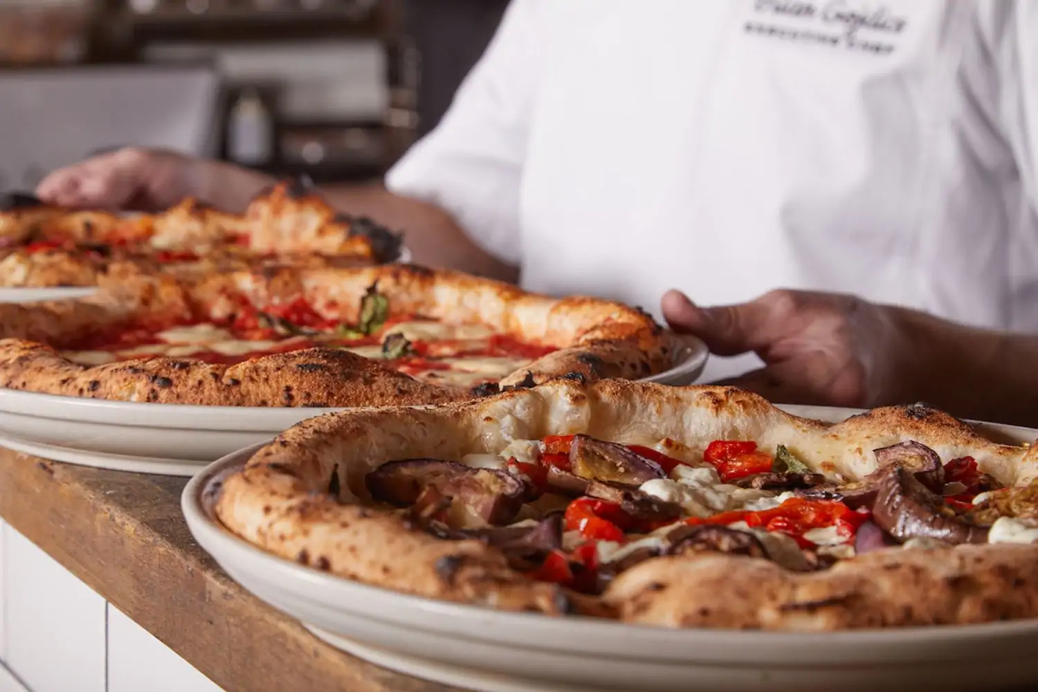 Two plates of fresh Neapolitan pizza with cheese and vegetable toppings at Tutta Bella in Seattle, one of the best family friendly restaurants in Seattle on OpenTable.