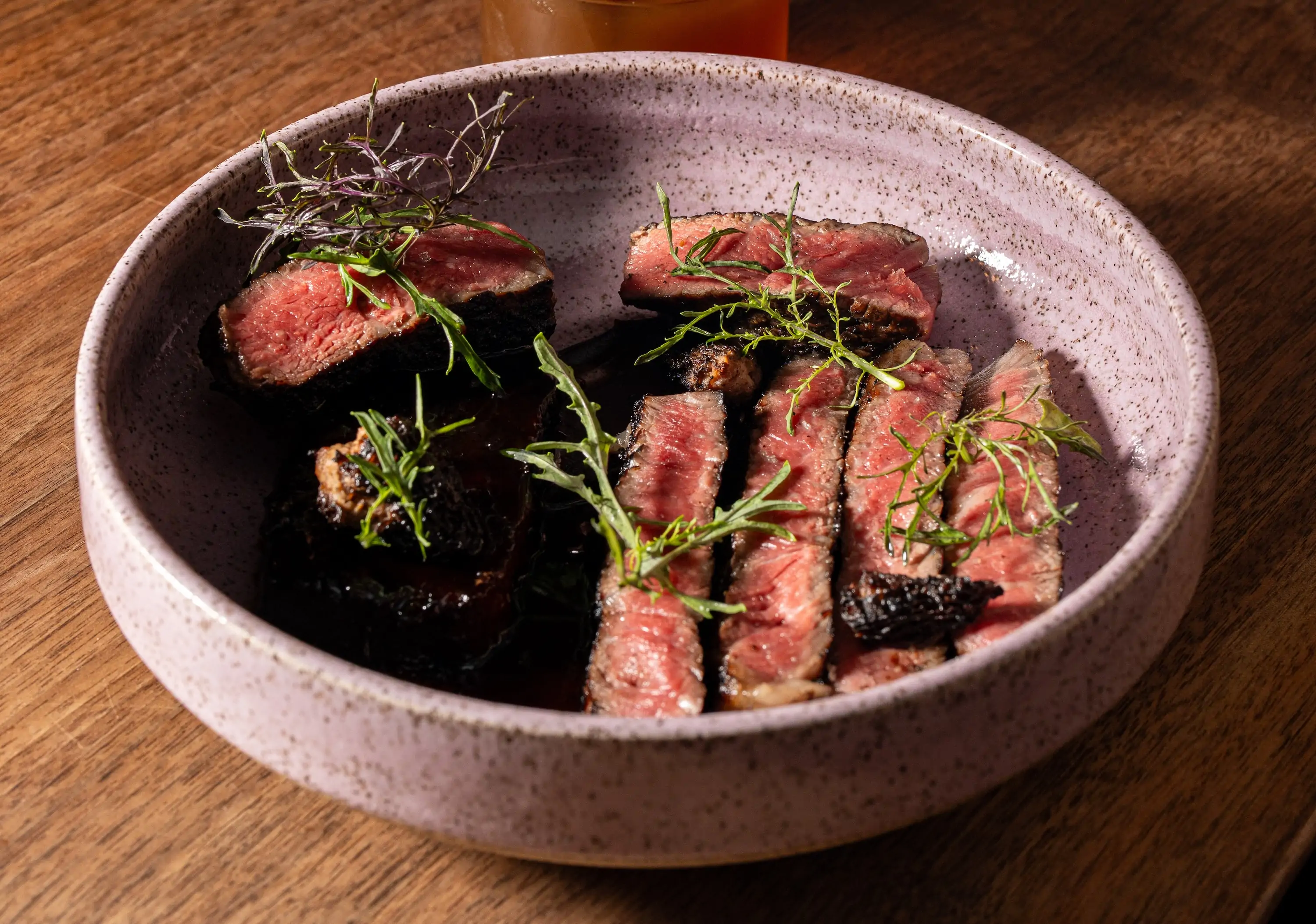 Thinly sliced ribeye with a brown sauce in a pink plate at Philadelphia restaurant Emmett