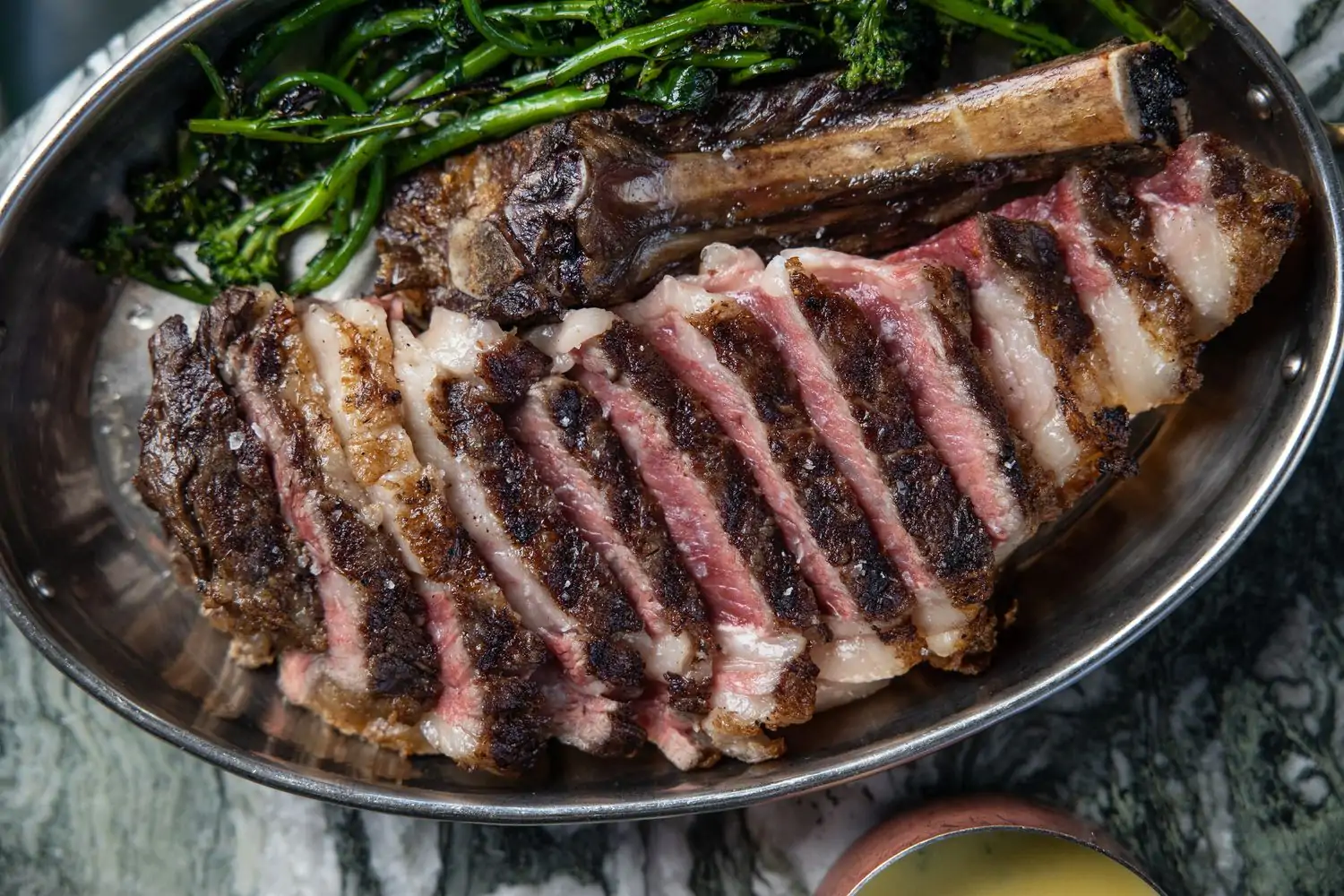 Sliced steak in a metal pan with some greens at Hollywood restaurant Gwen