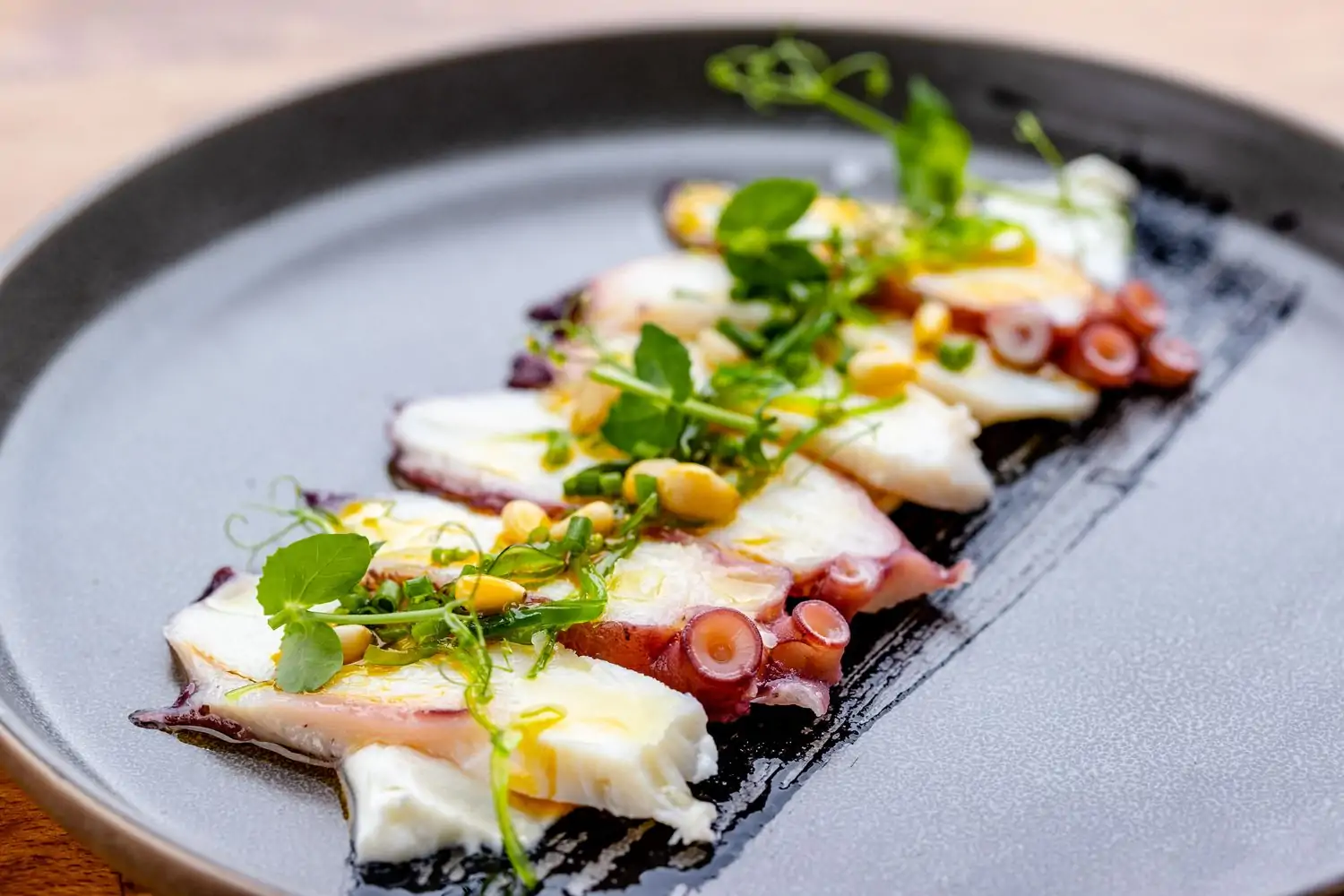 A plate of sliced octopus garnished with watercress and corn kernels at La Pulperia, NYC, on OpenTable.