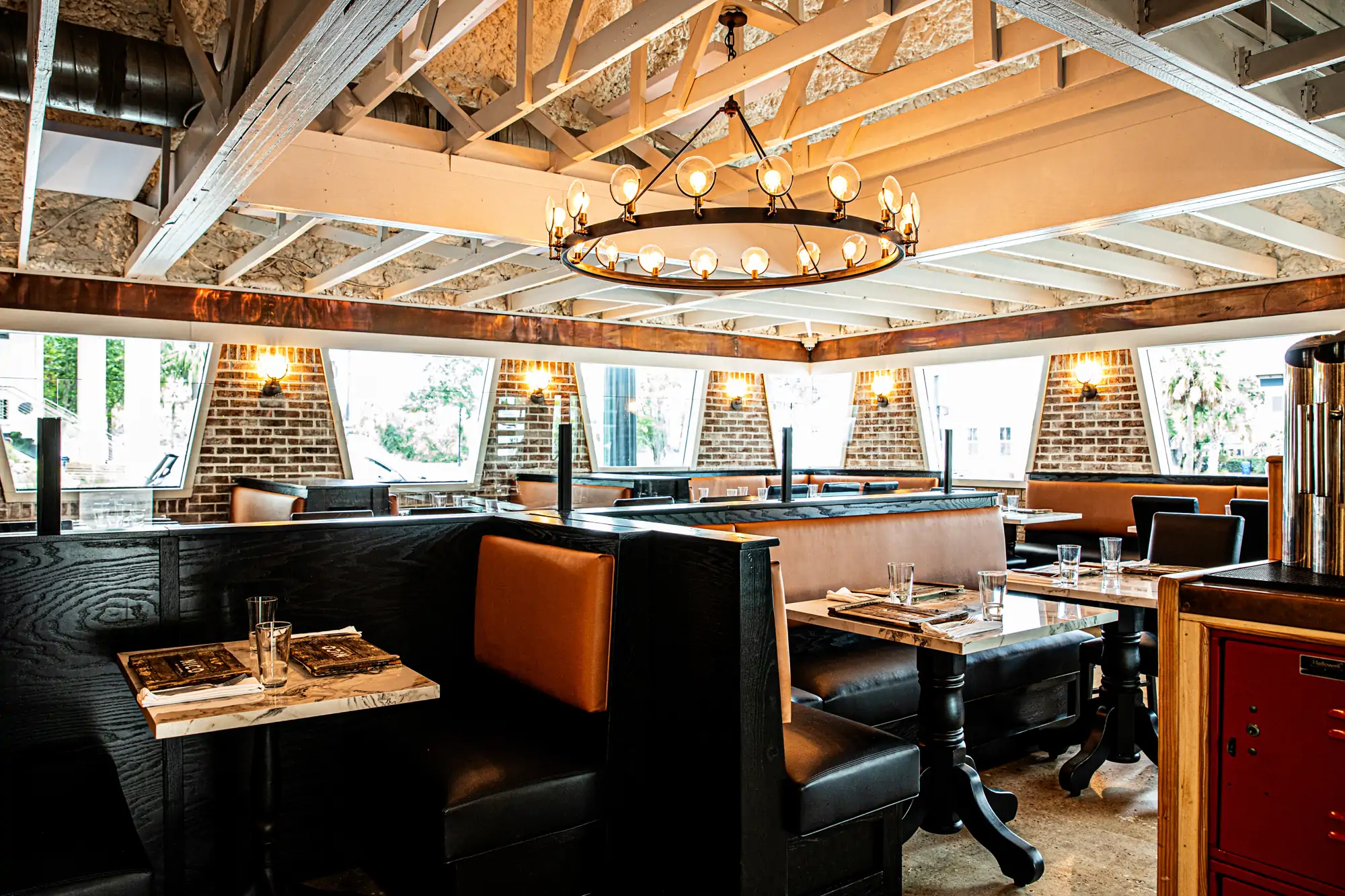The interior of Charleston restaurant NICO Oysters + Seafood seen here with black booths and a wooden ceiling