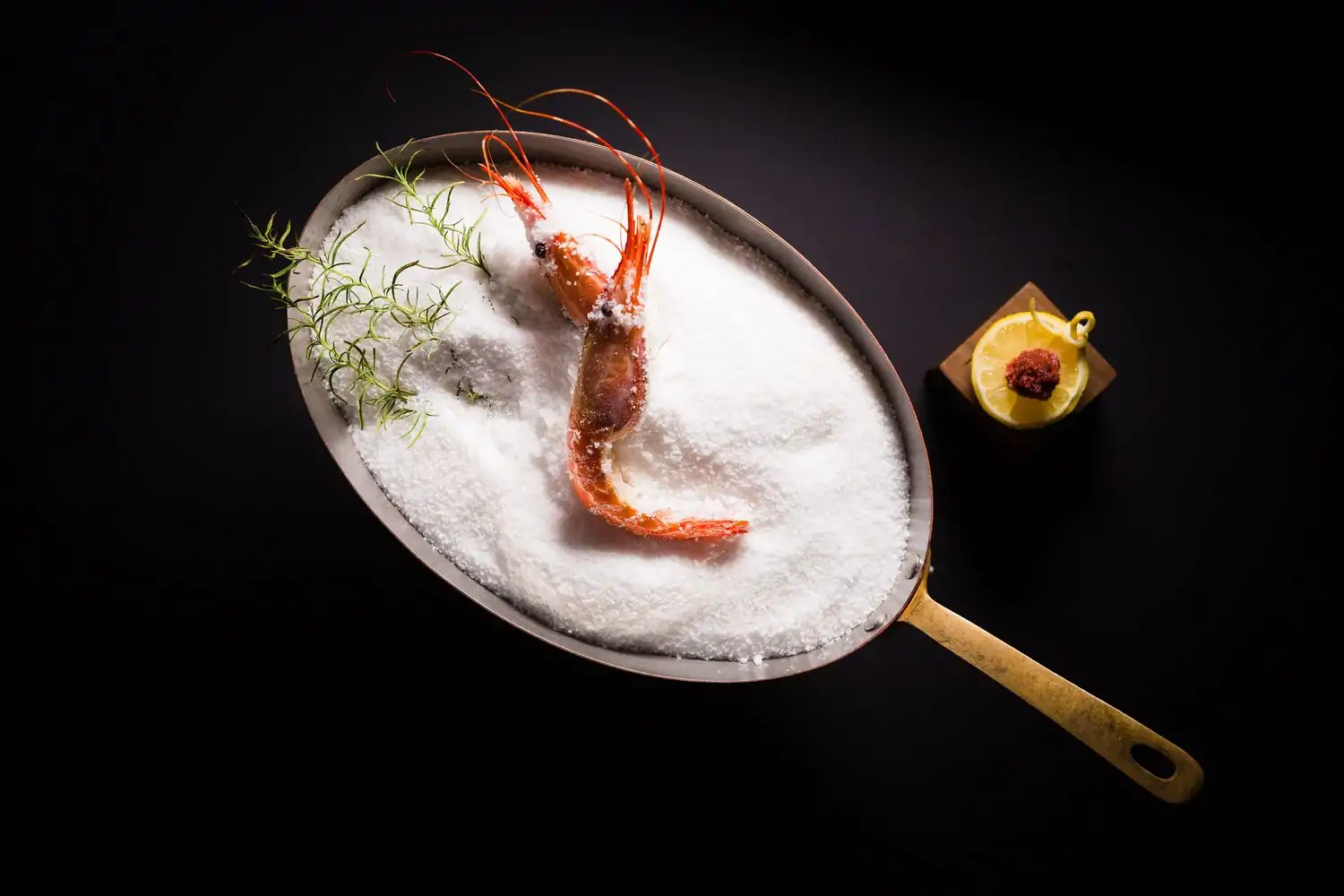 A shrimp in a plate of salt at Los Angeles restaurant Providence