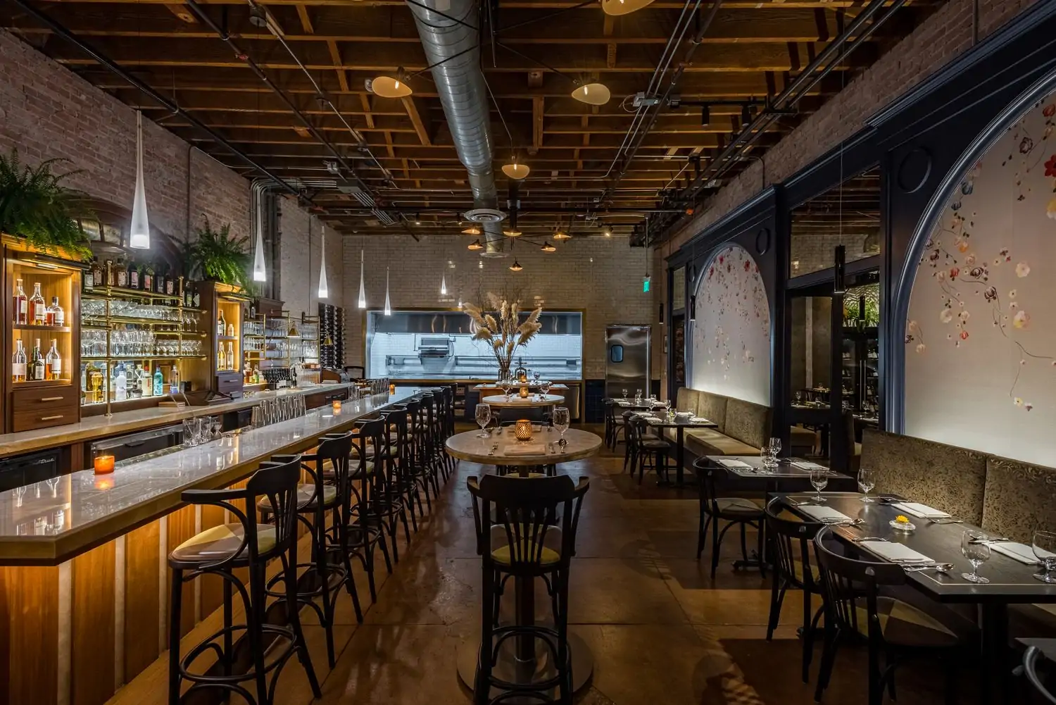 The interior of Los Angeles restaurant pasjoli with a marble bar on the left and booths and chairs on the right