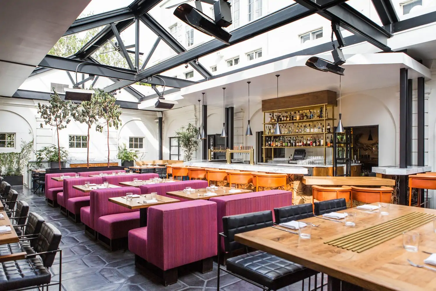The interior of Los Angeles restaurant Redbird with purple couches and a glass arched ceiling above