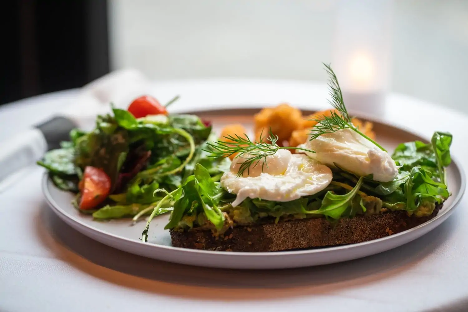 Avocado toast topped with arugula and poached eggs at Rise Bar, NYC on OpenTable.