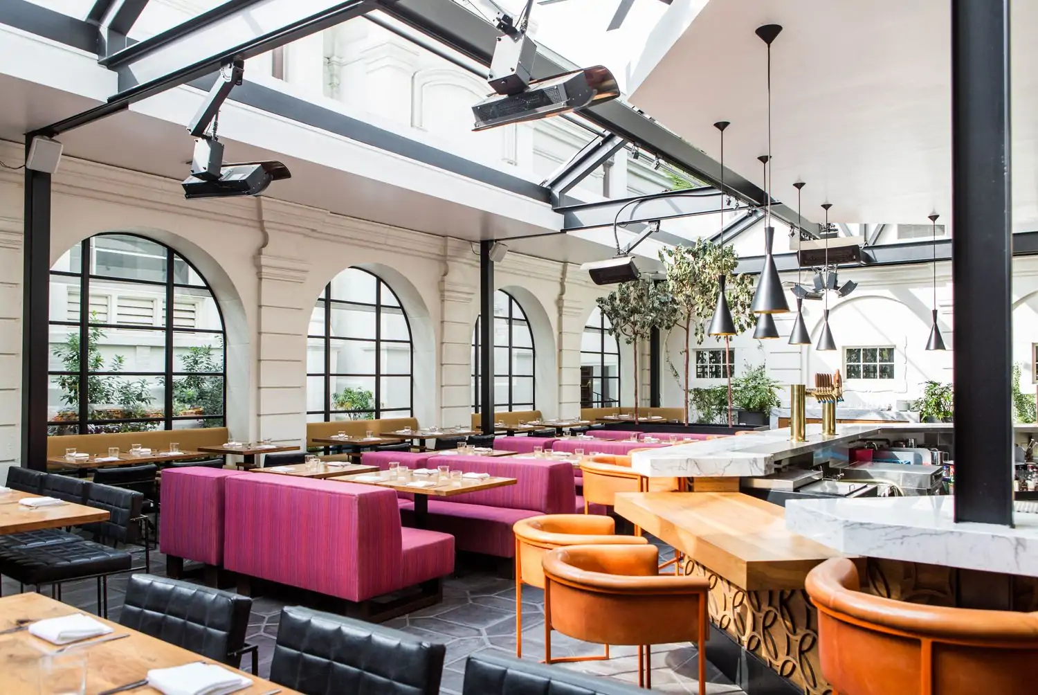 The interior of Los Angeles restaurant Redbird with a skylight on top and purple couches