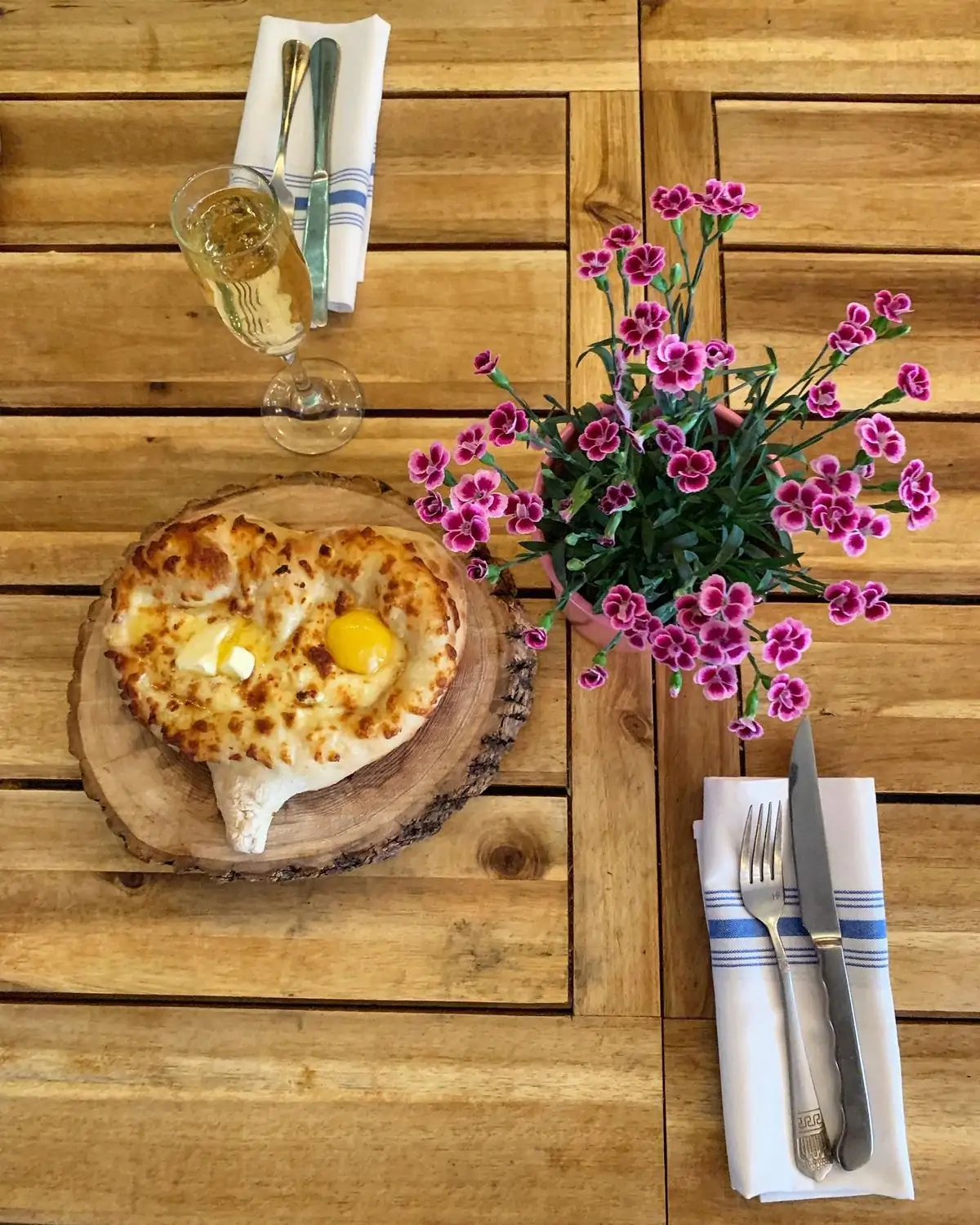 A cheesebread, a glass of wine, and a bouquet of purple flowers at Cheeseboat in Hell’s Kitchen, NYC, on OpenTable.