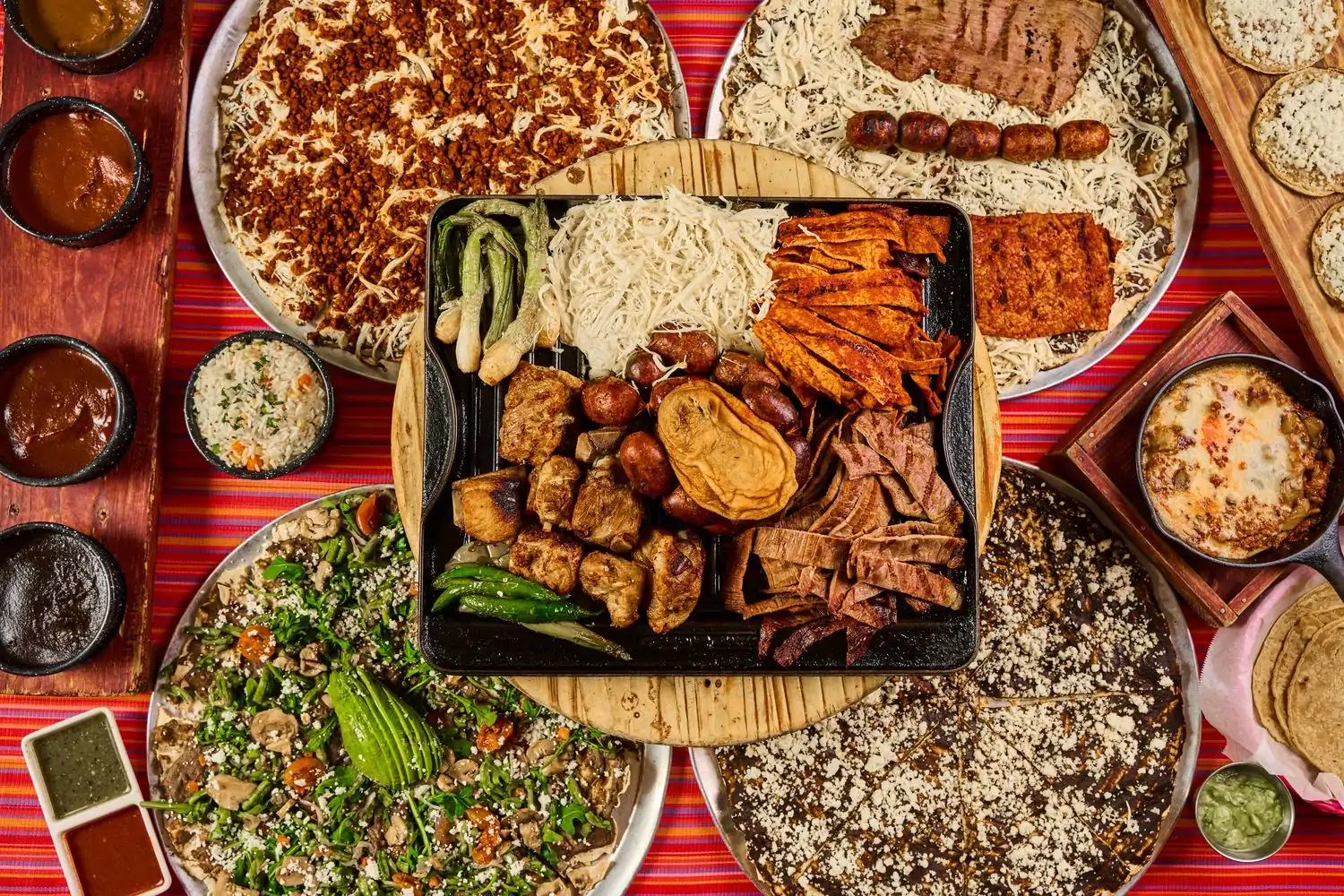 Several plates of Oaxacan food on a colorful table at Los Angeles restaurant Guelaguetza