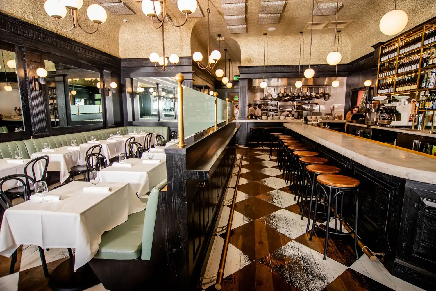 The interior of Los Angeles restaurant Petit Trois Le Valley featuring tall ceilings and green booths