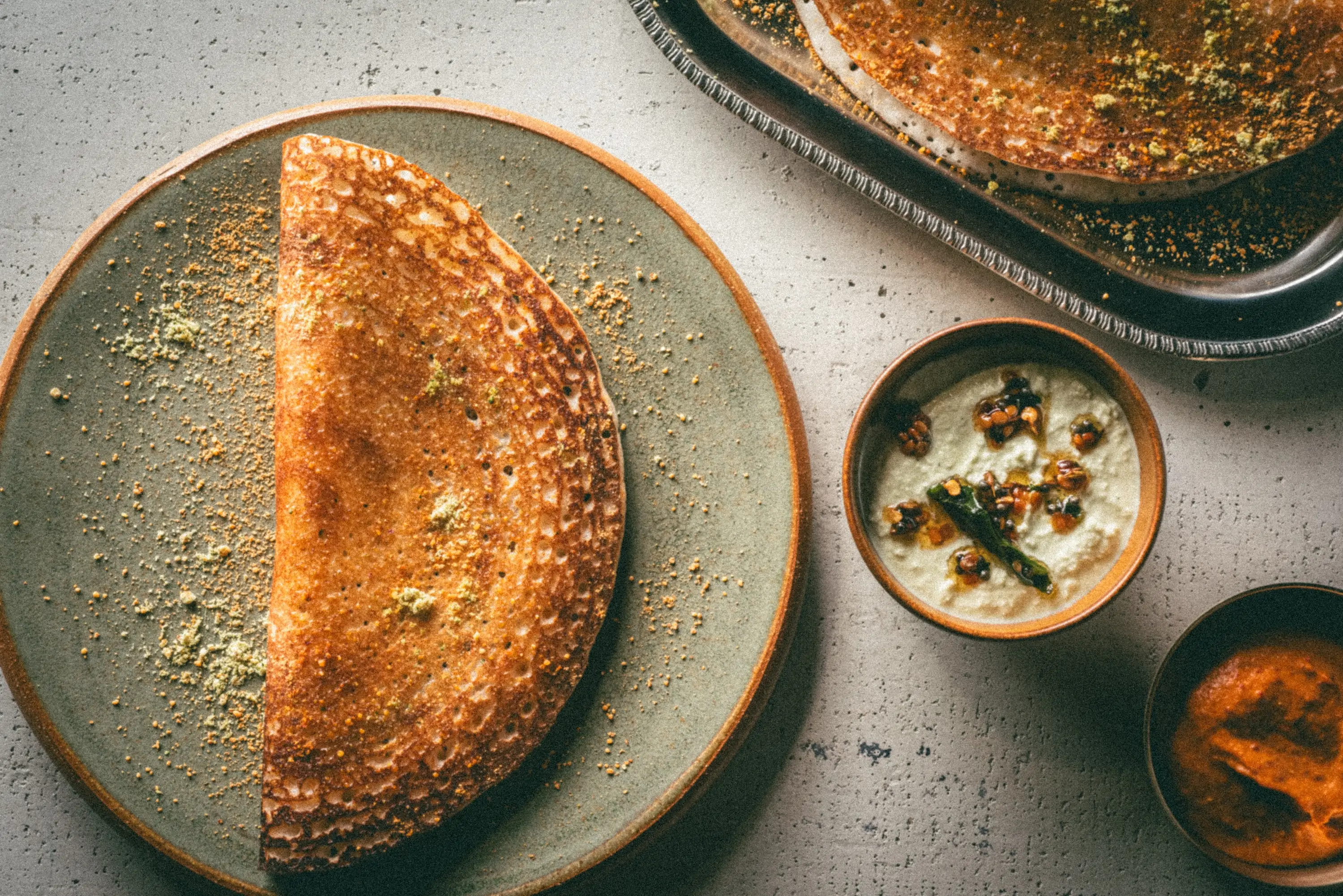 A dosa next to a coconut and tomato chutney at Chicago restaurant NADU