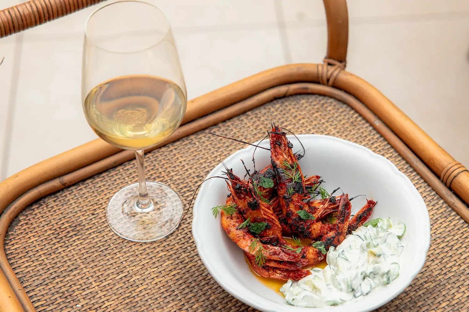 A shrimp dish next to a glass of white wine at Los Angeles restaurant Bavel