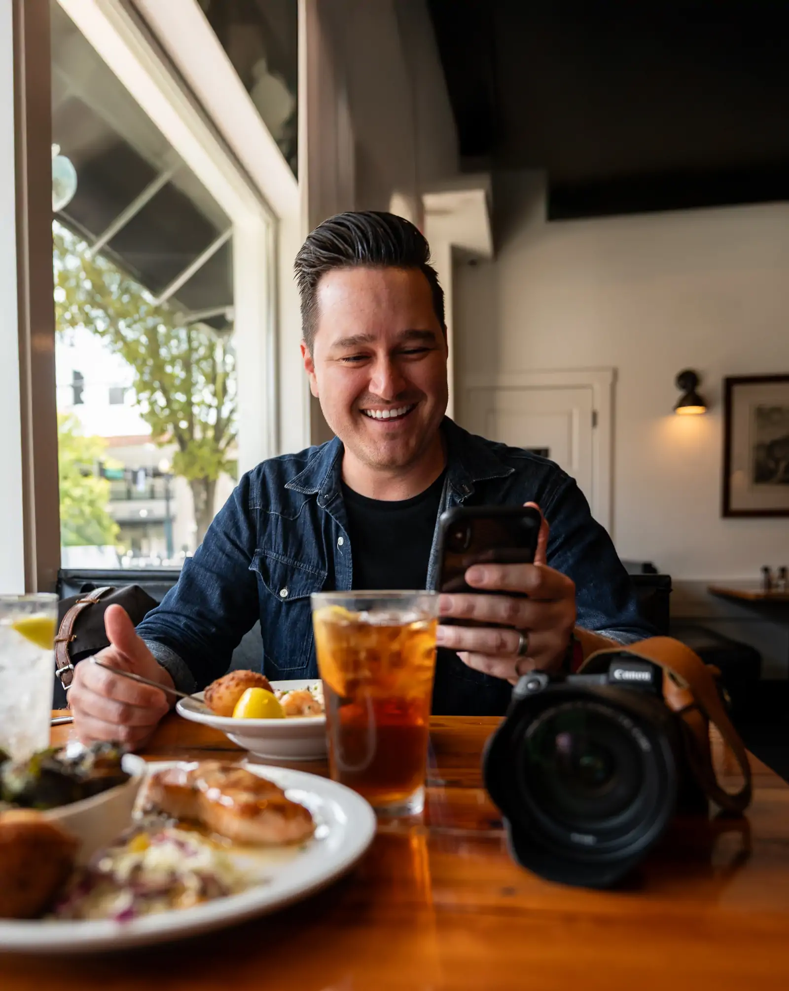The food blogger Eddie Sanchez sitting with his camera on a dining table at a restaurant in Los Angeles