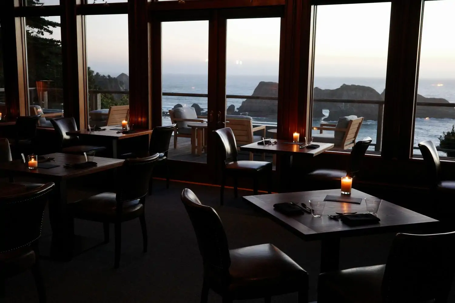 Diners in the dining room of Harbor House Inn with views of the Pacific coast in the background