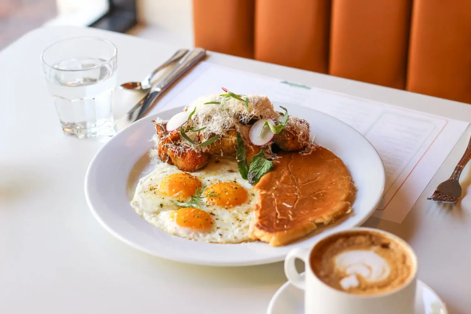A plate containing fried eggs, pancakes, and croquetas at Chug’s Diner, Miami, available on OpenTable.
