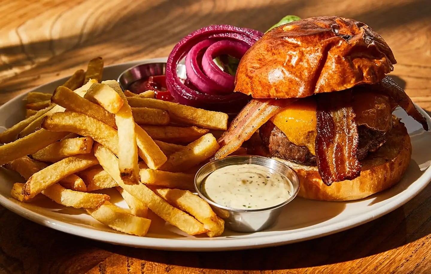 A burger with French fries next to it on a white plate at San Francisco restaurant Nopa