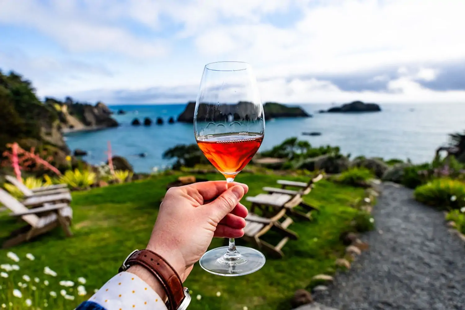 A man holding a glass of wine overlooking the Pacific Ocean at the Harbor House Inn