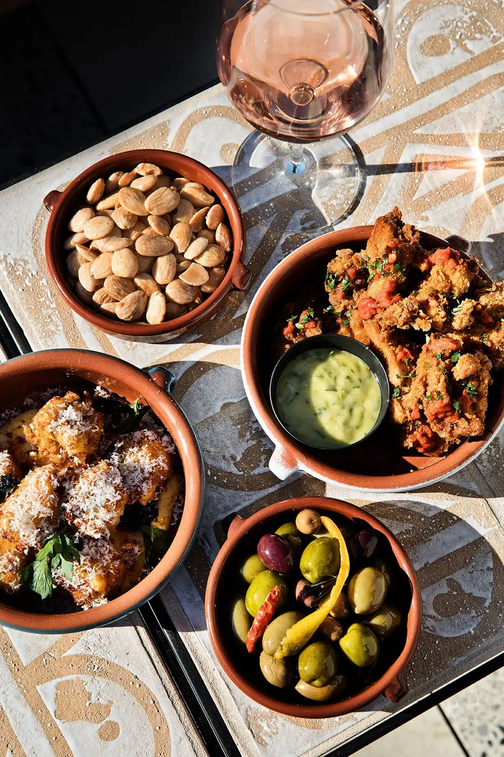 Plates of almonds, peri peri fried chicken, marinated olives, and charred cauliflower at Cara Cara, in Los Angeles. Available on OpenTable.