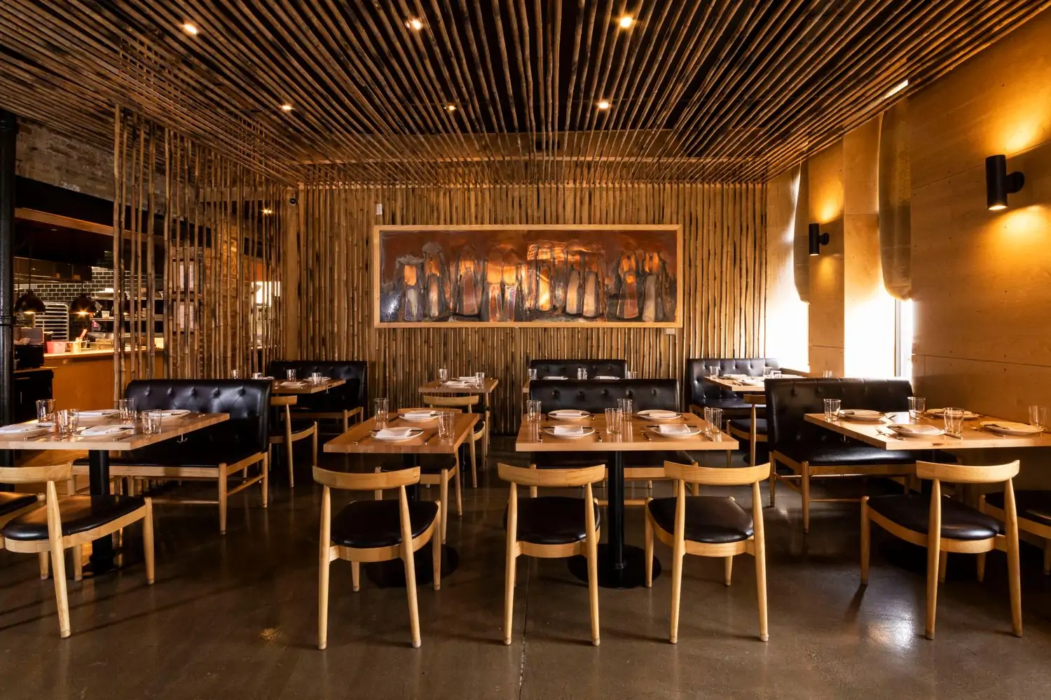 The interior of Chicago restaurant HaiSous Vietnamese Kitchen seen here with wooden tables and black leather-clad chairs