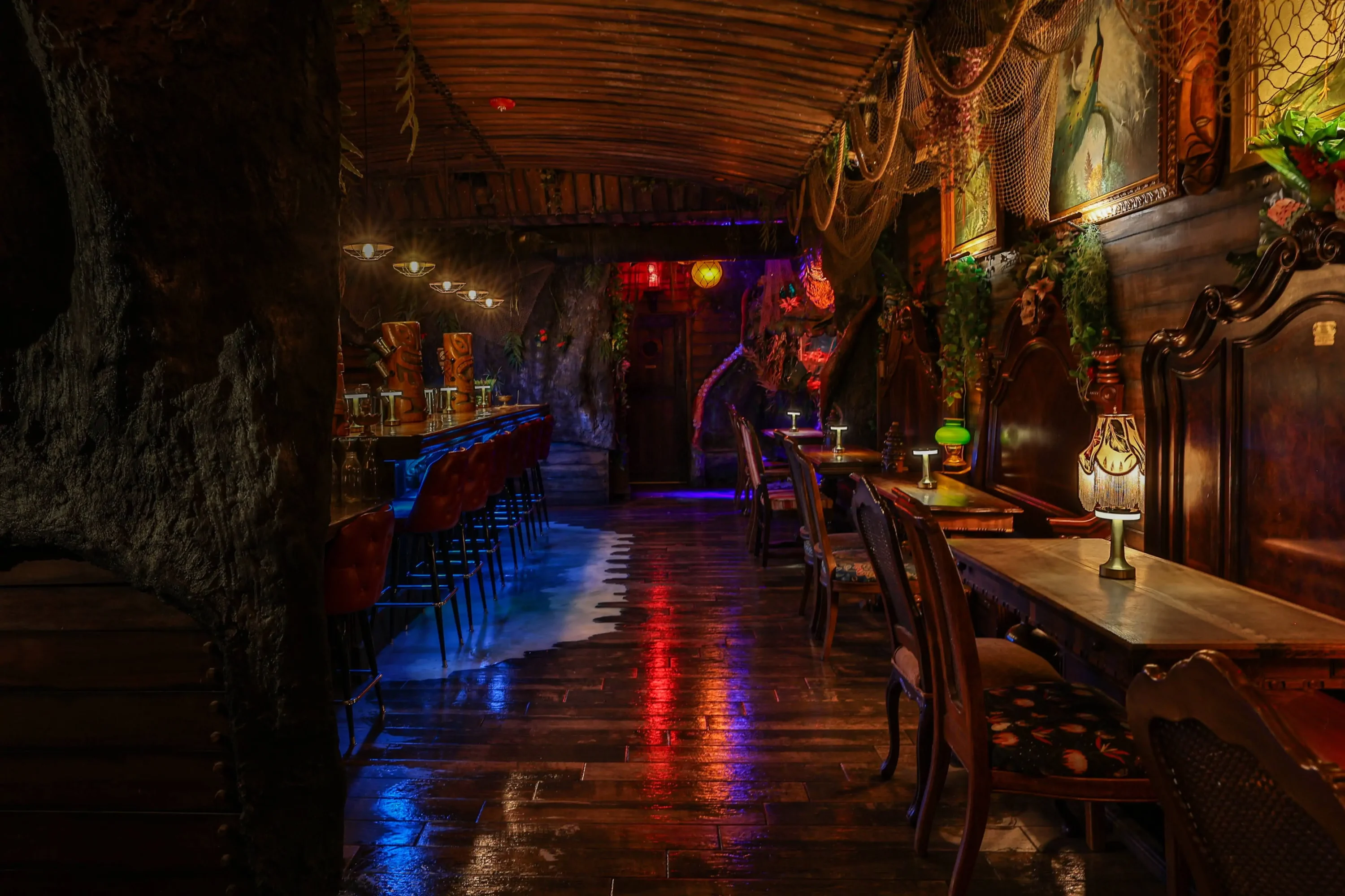 The dining area of Anaheim restaurant Strong Water featuring a bar on the left and wooden tables and chairs on the right