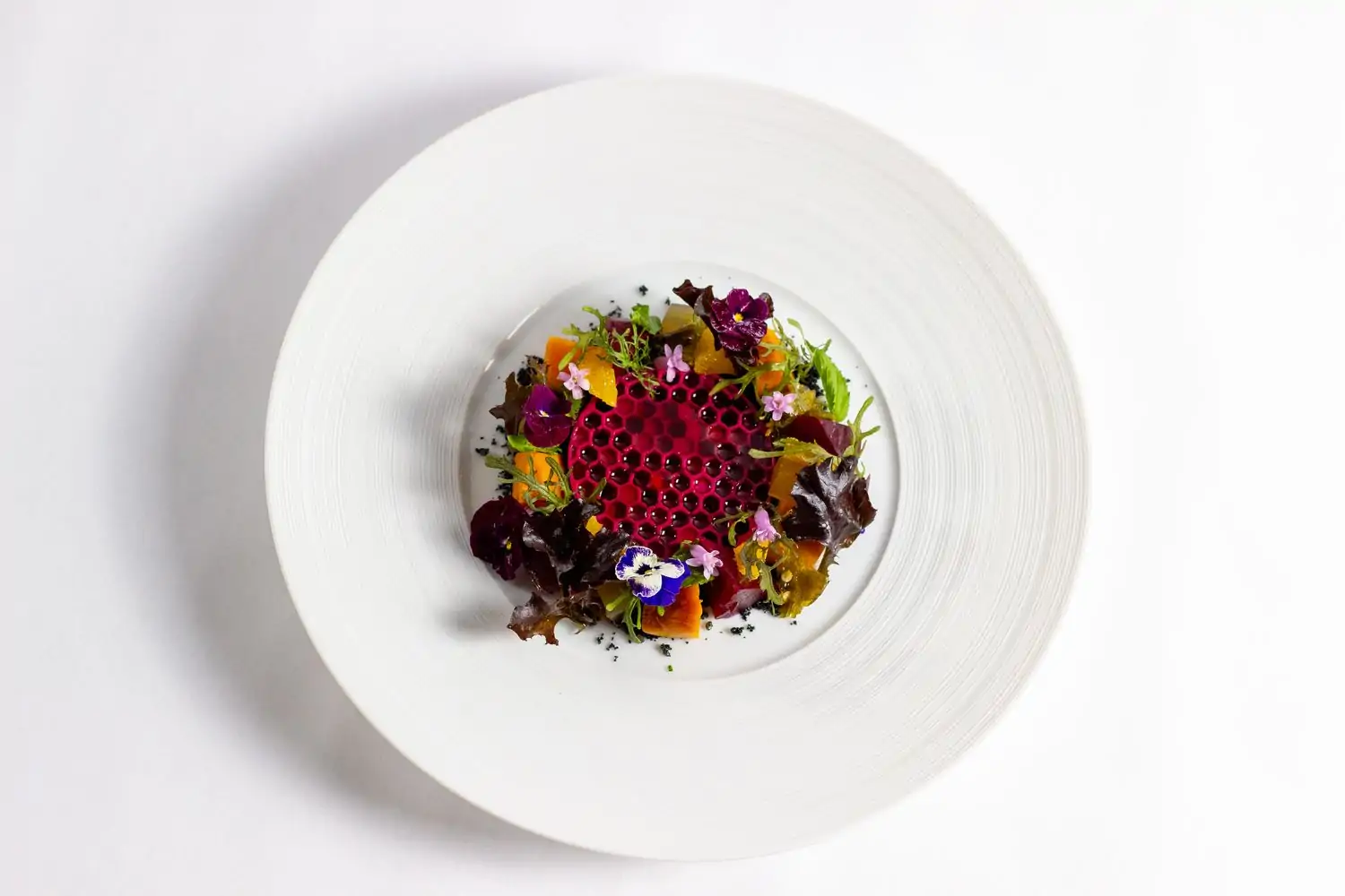 A plate with a pink honeycomb surrounded by colorful salad leaves at Ariete, one of the best restaurants in Coconut Grove, Miami. Book on OpenTable.