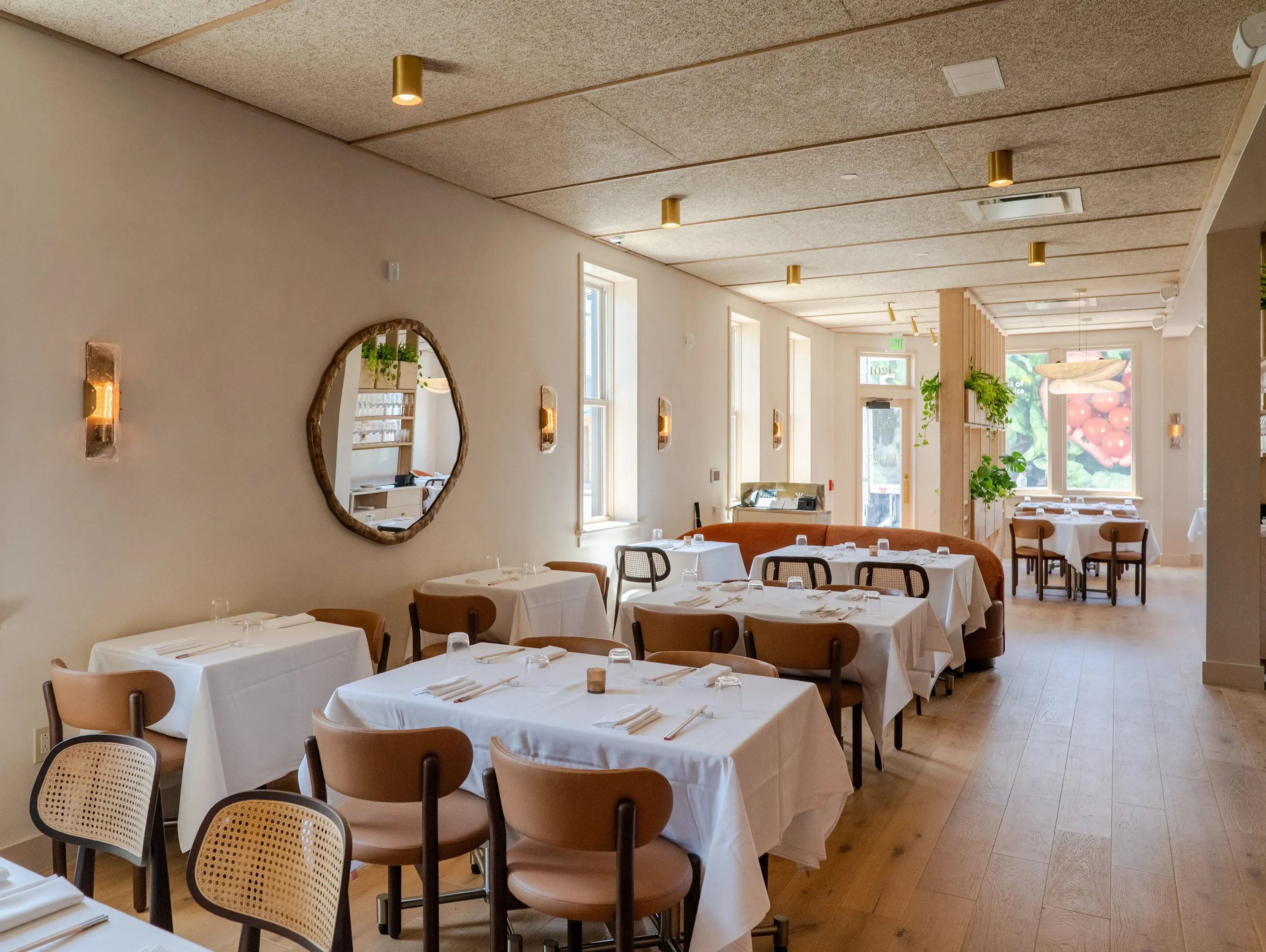 The interior of New Orleans restaurant The Kingsway featuring earth tones and windows looking out on Magazine Street