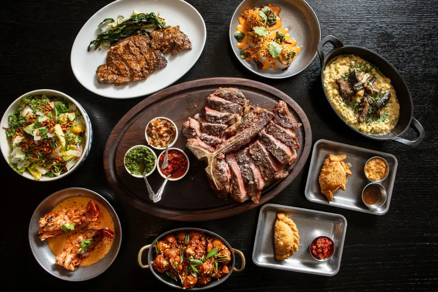 Steaks and other plates of food on a table at Chicago restaurant El Che Steakhouse & Bar