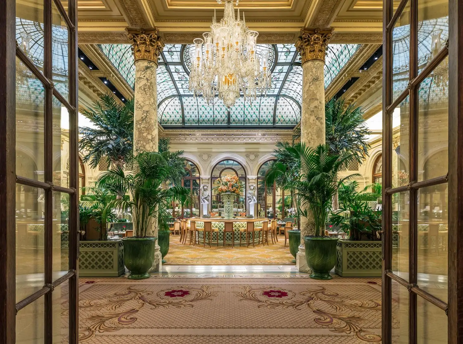 A crystal chandelier and stained-glass dome over the opulent dining room of The Palm Court, an OpenTable restaurant in NYC.