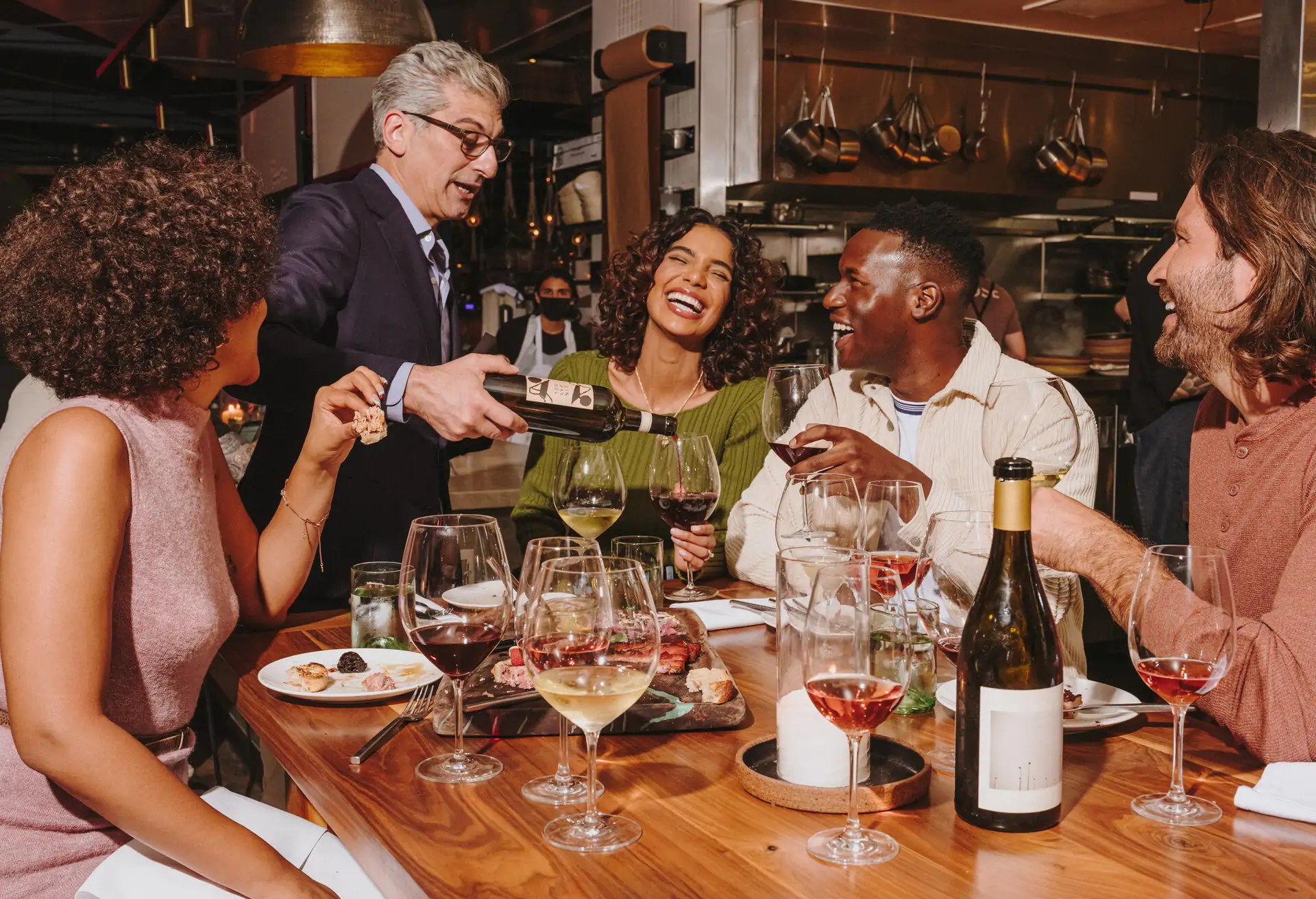 server serving customers at a restaurant table and customers are smiling while being served.
