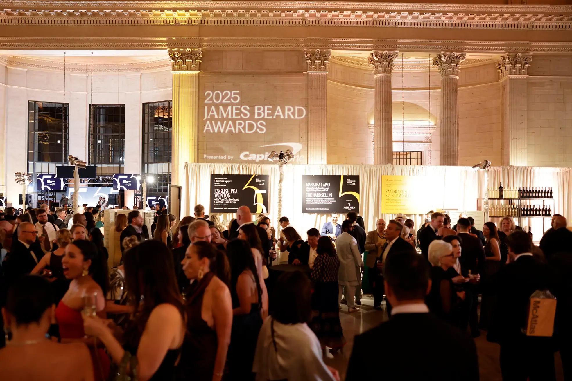 A crowd of attendees mingling at the 2025 James Beard Awards, held in a grand hall with classical architecture.